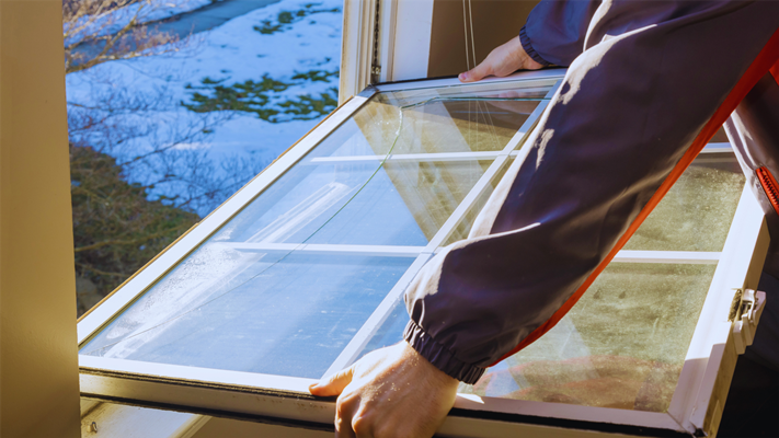 A homeowner removing a broken window to prepare for window replacement in NJ. 