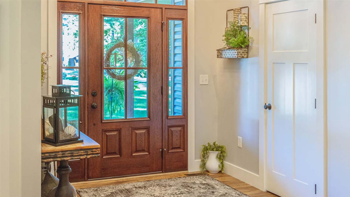 A modern entry door with glass inserts and sidelights, allowing sunlight to illuminate the interior foyer.  