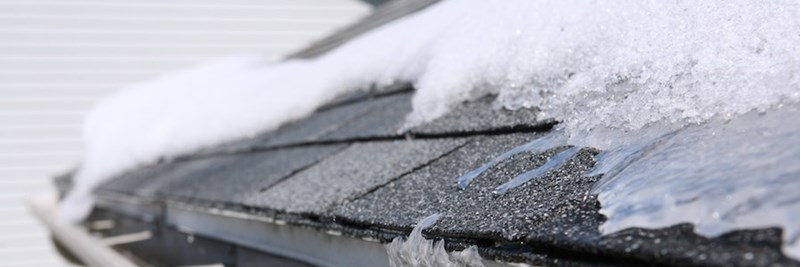 Ice on snowy roof with asphalt shingles